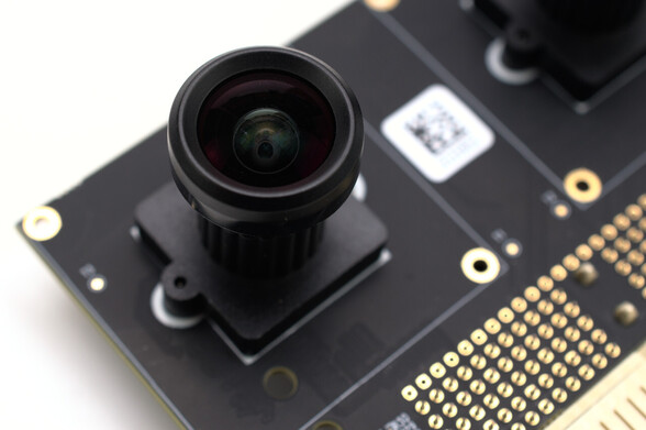A macro photo of one of the camera lenses on the PolarFire Video Kit camera board. The lens is heavily curved, suggesting a wide angle.