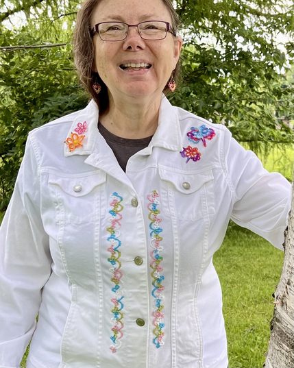 White jeans jacket front embellished with colorful tatted lace butterflies, flowers, and edging.