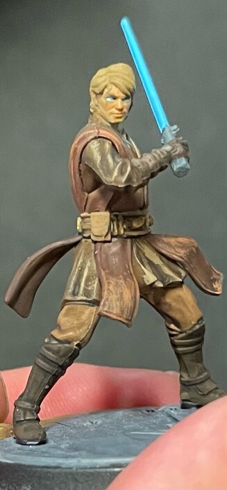 An Anakin Skywalker mini. His robes are many different shades of brown. His eyes and light saber are bright blue. 