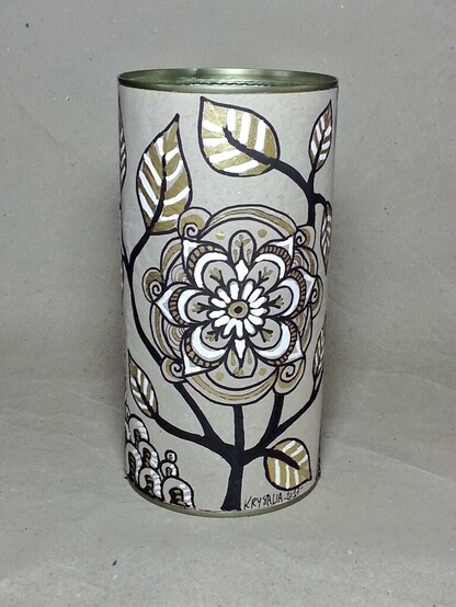 Sur un fond gris de papier recyclé grège, une boîte cylindrique est entouré d'un papier recyclé décoré avec un motif végétal en noir blanc et or.

Ce sont des sortes de fleurs extravagantes et imaginaires, un peu naïves, avec des feuilles rayées de blanc et des tiges noires. 

Le doré sur la boîte va bien avec le métal de la boîte elle-même qui est transparaît en haut là où le couvercle plastique doit se fermer. Et le couvercle n'est pas présent à l'image. 

On peut voir que le bord interne de la boîte a été plié avec des pinces de façon à ne pas présenter de surface coupante. 

Le tout forme un kit de crochet décoré, et a été garni comme indiqué dans le post. 