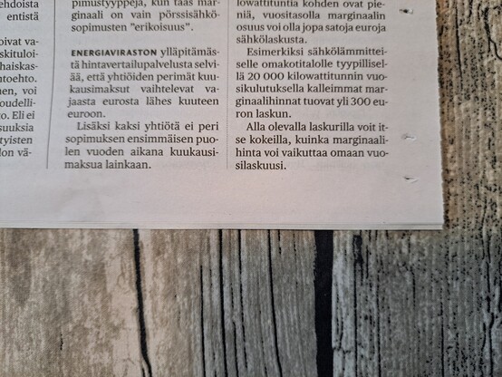 Paperinen sanomalehden sivu pöydällä. Sivun viimeinen kappale: "Alla olevalla laskurilla voit itse kokeilla, kuinka marginaalihinta vaikuttaa omaan vuosilaskuusi."