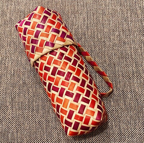 Picture of a woven basket pen case with natural, pink, and purple strips braided together