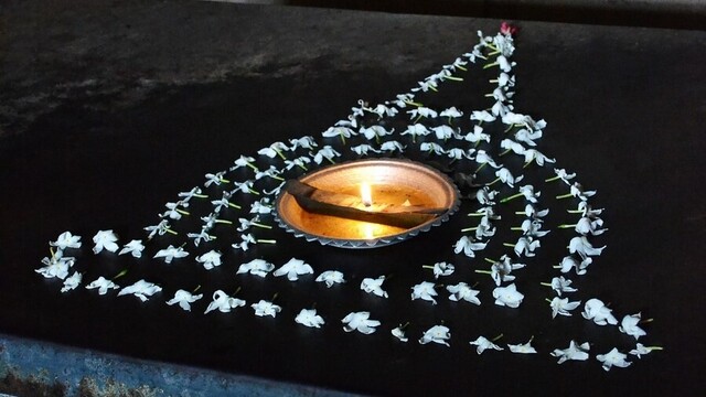 An oil lamp offered with a design of a stupa surrounding it made out of jasmine flowers.