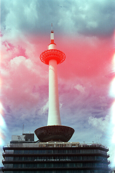 35mm color photo of the Kyoto Tower Hotel with a big red glowy effect from a light leak across the spire in the middle of the image.
