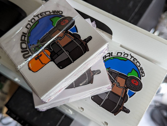 A pile of square stickers with the worldo techno music device on