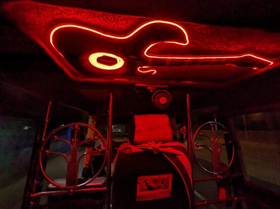 An interior of an auto rickshaw with a guitar shaped decoration with red light makes the whole interior spilled with red color.  Night time.