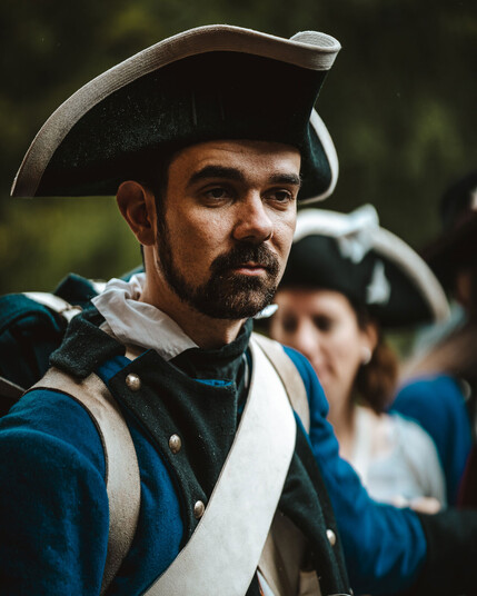 Bärtiger Mann in der Kleidung der französischen Marineinfanterie des 18. Jahrhunderts mit blauer Uniformjacke und schwarzem Dreispitz.