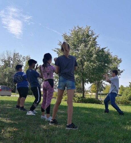 Kinder üben Tai Chi auf einer Wiese.
