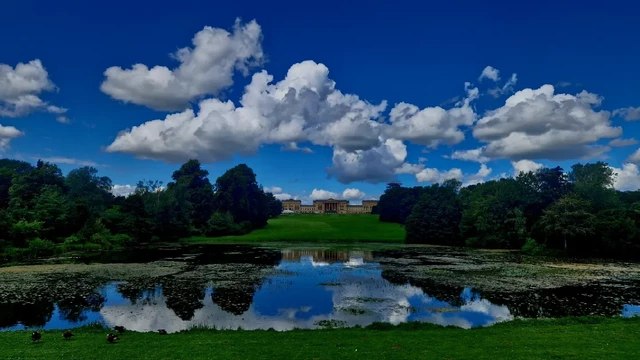 Stowe House with lake & clouds over a blue sky