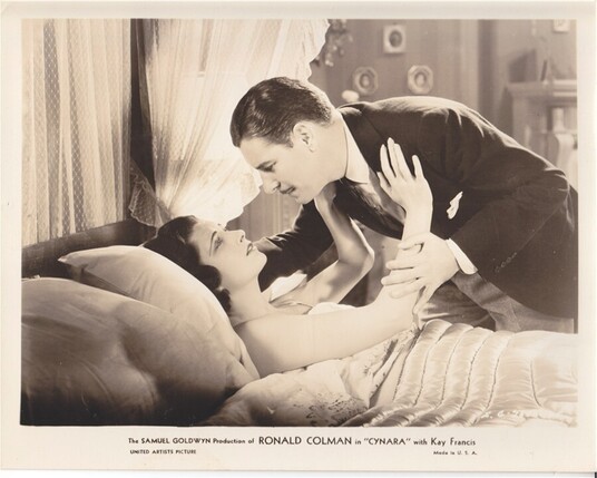 Ronald Colman standing over Kay Francis who is in bed the 1932 pre code romantic drama “Cynara”