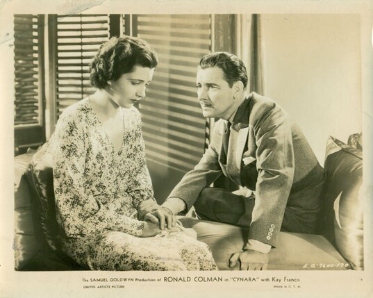 Ronald Colman and Kay Francis sitting on a bench in the 1932 pre code romantic drama “Cynara”.