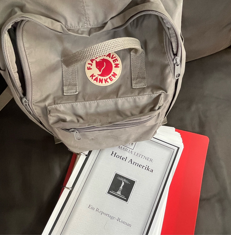 grauer rucksack mit kopie des buches »hotel amerika« von maria leitner