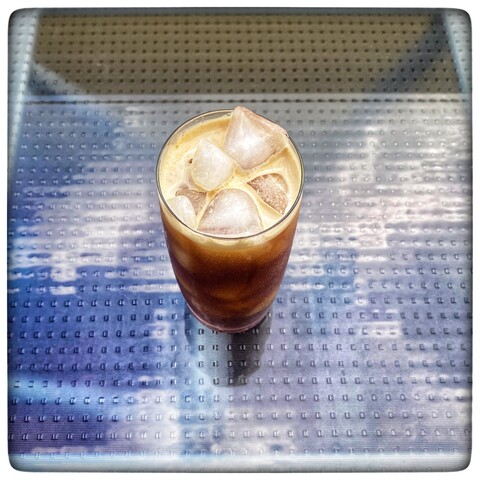 Glass of espresso-tonic with ice on a table.
