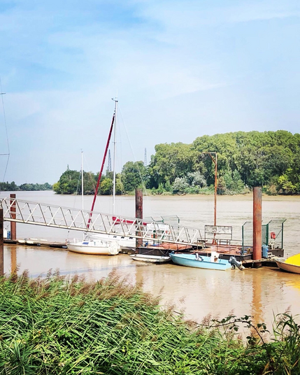 Ponton et petits voiliers accostés sur la rivière 