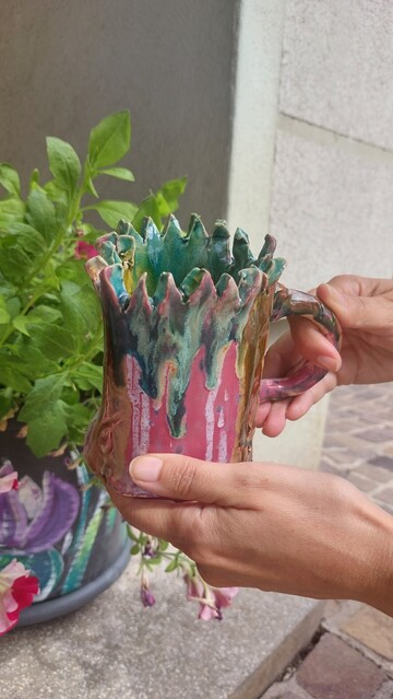 Bunte handgetöpferte Tasse mit stark gezacktem Rand.