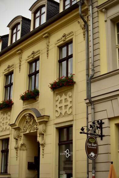 Beige plaster and stone house front with flower boxes in windows 