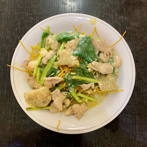 A plate of mie titi noodles with chicken, bakso, and greens.