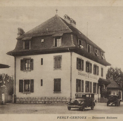 A sepia photo of the Swiss border post house, with old-style cars in front.