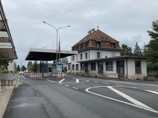 The same building as the previous photo, today. The building has been extended on both ends. An ugly covered portico covers the road, providing cover for the Swiss border guards. The photo is taken from the French side.