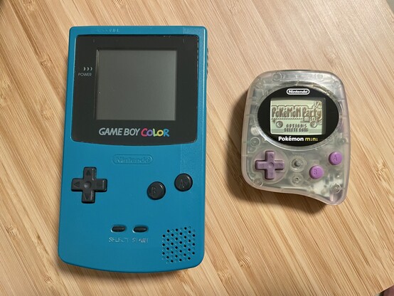 A GameBoy Color in teal and a purple Pokémon Mini console.