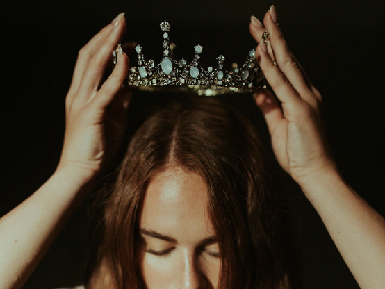 Close-up photo of a woman placing a crown on her head