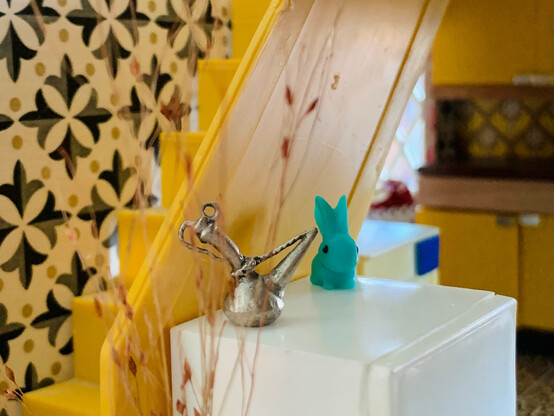A tiny SylvaC-style rabbit ornament on a Lundby fridge with retro 60s wallpaper in the background.