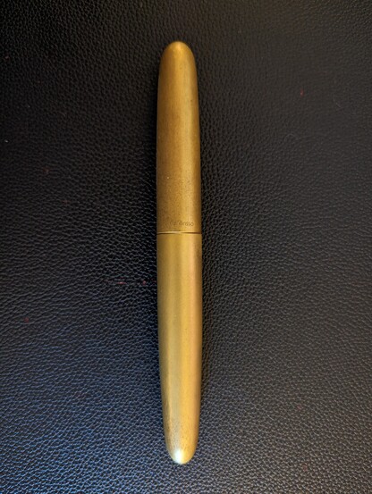 Posted brass Ensso Piuma fountain pen on a black textured mat