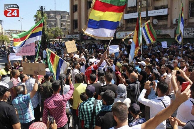 Image publiée le 27 août 2023 par la chaîne de télévision Suwayda24 de manifestants brandissant des drapeaux druzes dans la ville de Soueida, en Syrie. © Photo Suwayda24 via AP / Sipa