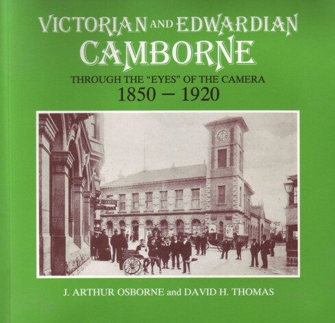 The front cover of 'Victorian and Edwardian Camborne Through the Eyes of the Camera, 1850-1920' by J. Arthur Osborne and David H. Thomas. Green with title and a large sepia photograph of the Market House and clock tower in Camborne at about the turn of the 20th century to the centre.