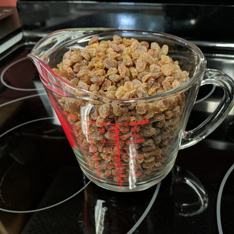 Mostly de-stemmed dehydrated green grapes, after working by hand and a mixer to remove most of the stems, they don't look as dark now after being roughed up a little. There are still a few stems present. They are in a glass measuring cup and exceed 1 quart of volume.