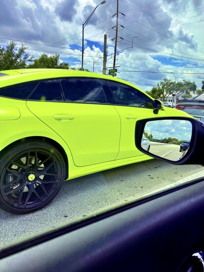 Shooting out the window of my own car, looking at an adjacent high performance sports car with very dark tinted windows and painted the most vibrant shade of chartreuse you can possibly imagine.