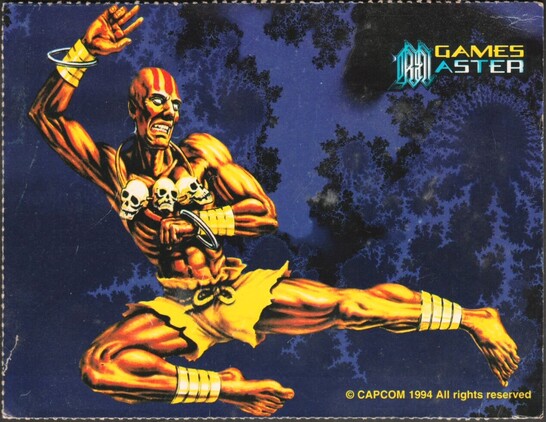 A printed colour postcard of Dhalsim from Street Fighter doing a flying kick against a blue Mandelbrot type background.