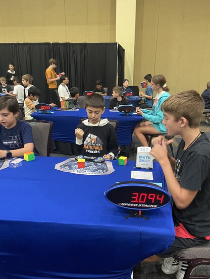 Competitor in 2x2x2 cubing competition celebrating personal record solve. Timer shows 3.094 seconds.
