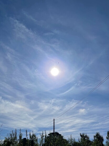 A bright sun hanging in blue skies on a warm late summer day.
