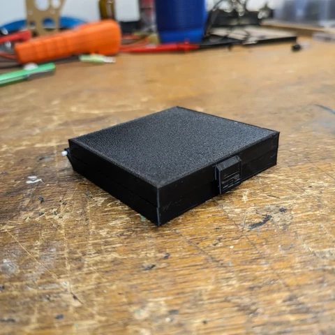 Small box, 65mm x 65mm x 16mm with integrated hinge and clasp. Shown closed here. Printed in black PLA.