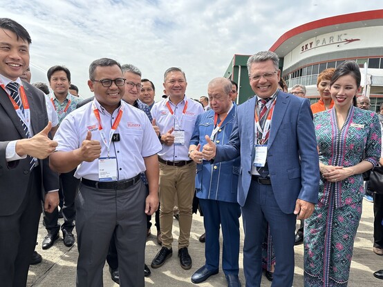 A group of people standing with smile and thumbs up.