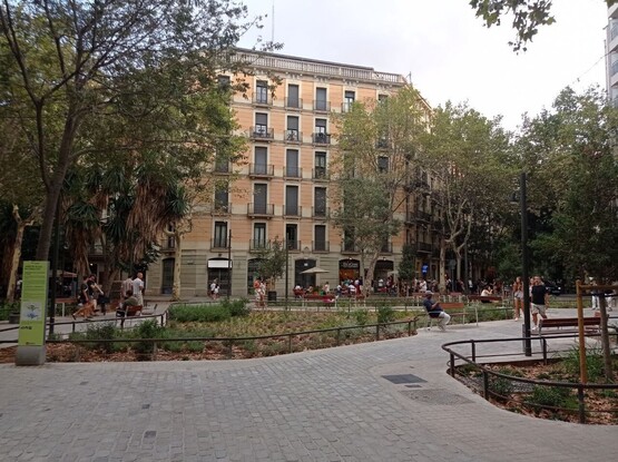 Una imagen de la superilla de consell de cent, donde destaca la antigua calzada convertida en acera, zonas ajardinadas y gente sentada y jugando a la sombra de los árboles