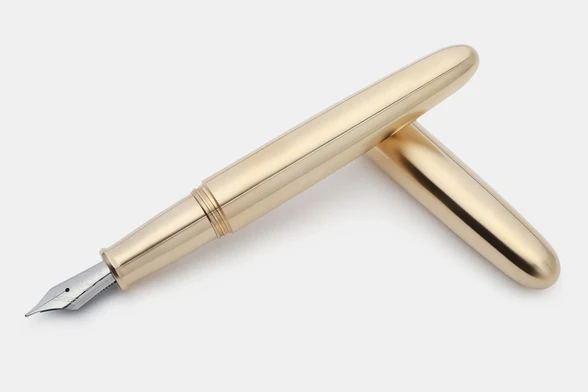 A product photograph of an Ensso PIUMA brass fountain pen with the barrel resting on the cap