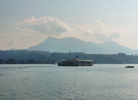 Ein Raddampfer auf dem Vierwaldstättersee. Dahinter Berge. 