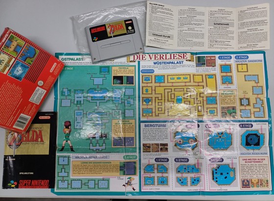A photo of a poster with the dungeons of "The Legend of Zelda - A Link to the Past".

Also seen in the photo: The game cartridge, the original box, the manual and the opened (top secret) solution booklet.