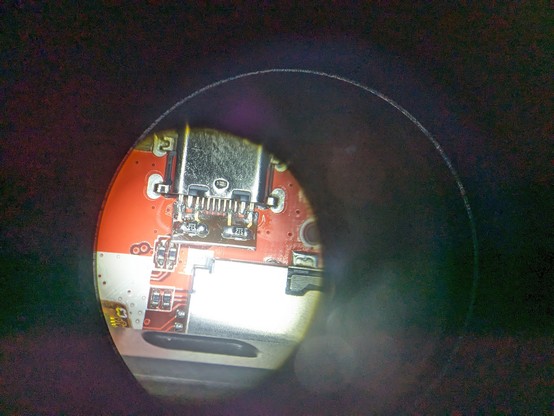 A USB C connector under I microscope showing a tiny flex PCB soldered to the connector adding the 5.1k resistor back