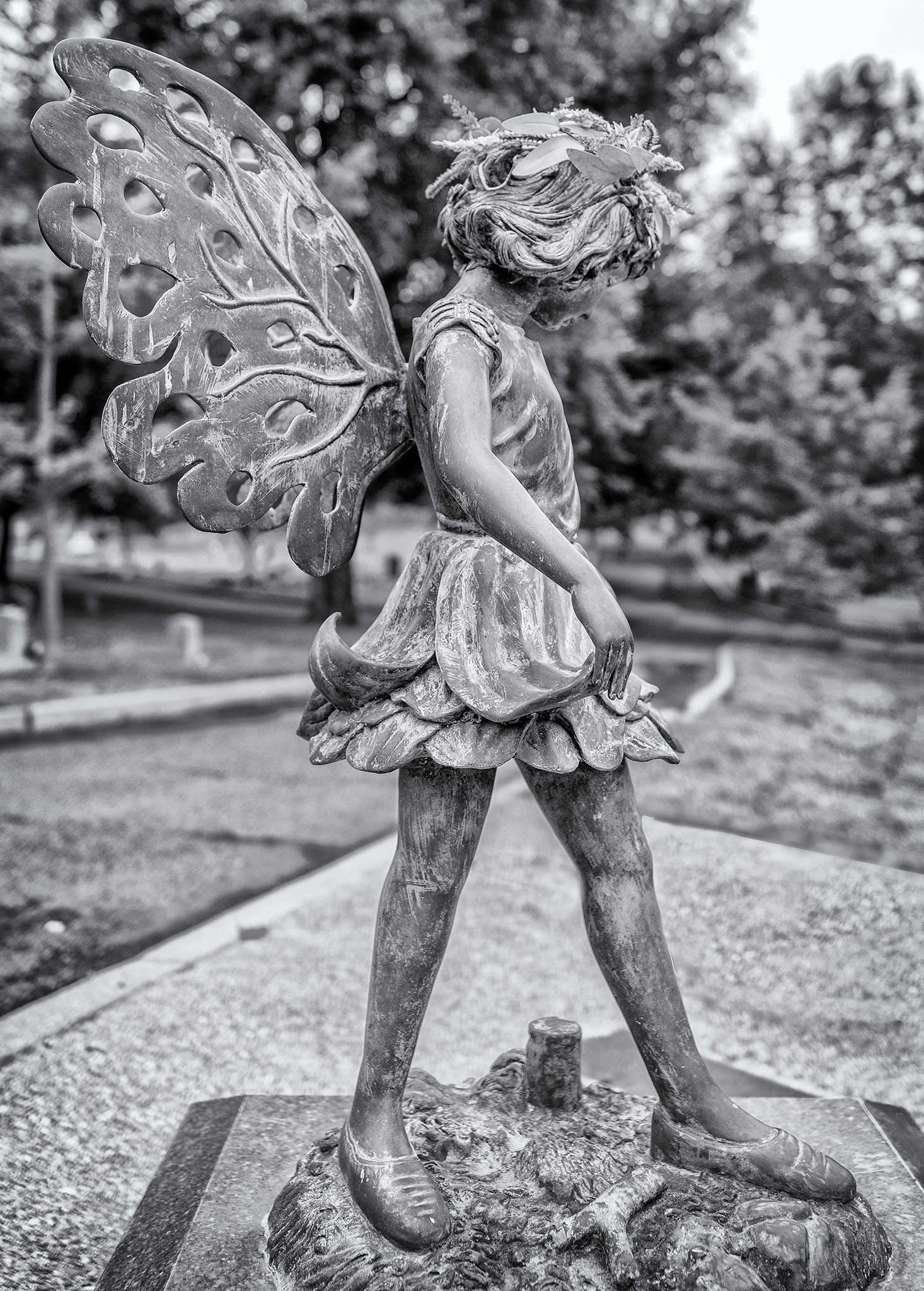 Metal statue of a young girl with butterfly wings atop a grave in the Tulocay cemetery in Napa, California.