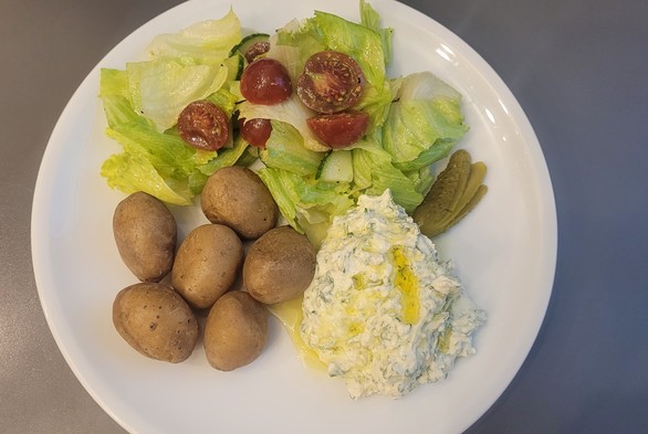 Farbfoto: das beschriebene Gericht mit einem Salat aus Eisberg, Gurke und Tomaten auf einem weißen Teller, von oben gesehen. 