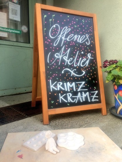 Eine Klapptafel steht vor der Ladentür. Sie kündigt das Offene Atelier und die Materialsammlung im LADEN Wurzen an.