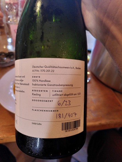Rückseite Sektflasche:

"Deutscher Qualitätsschaumwein, b.A Baden

Ernte:
100% Handlese
fraktionierte Ganztraubenpresse

Rebsorten:
Riesling

Tirage:
unfiltriert abgefüllt am: 5/21

Degorgement:
6/23

Flaschennummer:
181/407"