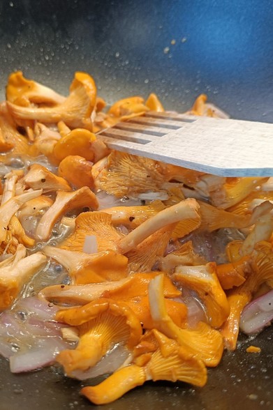 Red onion and chanterelles and black pepper on the wok pan 
