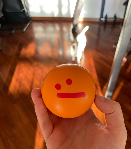 Orange stress ball with a ":/" draw moderately bright red design. This ball was given by Devrant to all users who reached 1k upvotes on a post.