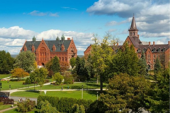A picture of the UVM green with two red-stone buildings visible in the back (Old Mill and Williams)