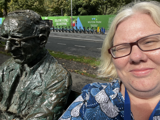 Me sitting beside a statue of poet Patrick Kavanagh. The statue is him sitting on a bench. 