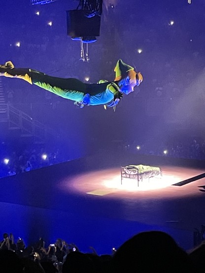 A giant Peter Pan soars over the center stage, which has only a bed with a child sleeping in it.